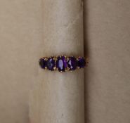 A 9ct yellow gold amethyst line ring set with five graduated oval amethysts to a claw setting and