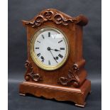 A Victorian walnut cased mantle clock, with an arched top, applied with scrolls and leaves,