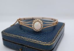 An opal and diamond hinged bangle, with an oval opal,