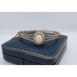 An opal and diamond hinged bangle, with an oval opal,