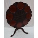 A 19th century mahogany tripod table with a carved top with eight separate plate wells on a