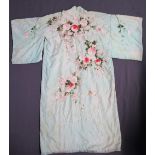 A Japanese silk kimono with embroidered decoration of flowers and leaves to a green ground
