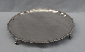 A George VI silver salver with beaded wavy edge on four ball and claw feet, 25cm diameter,