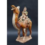 A Tang Dynasty style pottery statuette of a camel mounted with a bearded musician playing a