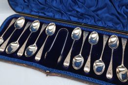 A set of twelve Victorian bright cut silver tea spoons and matching sugar nips in original box,