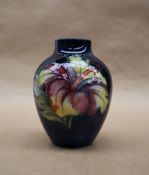A Moorcroft pottery vase, decorated in the Hibiscus pattern to a blue ground,