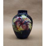 A Moorcroft pottery vase, decorated in the Hibiscus pattern to a blue ground,