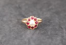 A ruby and pearl dress ring, with a central pearl and eight faceted rubies to a yellow metal mount,