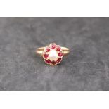 A ruby and pearl dress ring, with a central pearl and eight faceted rubies to a yellow metal mount,