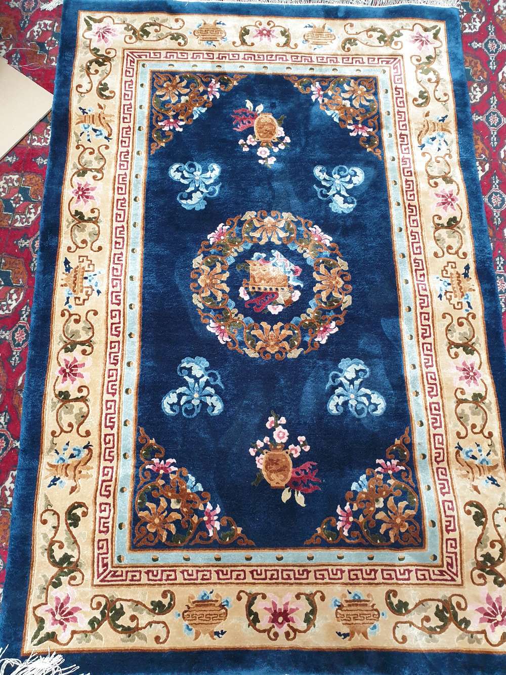 A Chinese rug with a blue ground decorated with vases of flowers ,