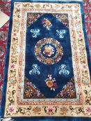 A Chinese rug with a blue ground decorated with vases of flowers ,