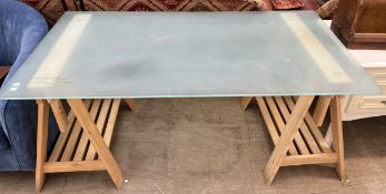 A glass topped table with trestle legs