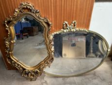 A brass framed wall mirror of oval form with bow surmount together with a gilt plaster wall mirror