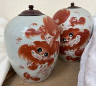 A pair of Chinese porcelain storage jars decorated with dogs of foo in iron red