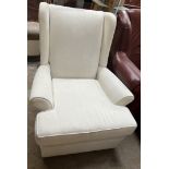 A cream upholstered wing back elbow chair