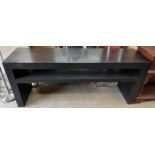 A black ash console table, with a rectangular top above a shelf on slab sides,