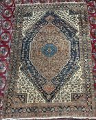 A Persian rug with a red ground and a large blue rimmed medallion,