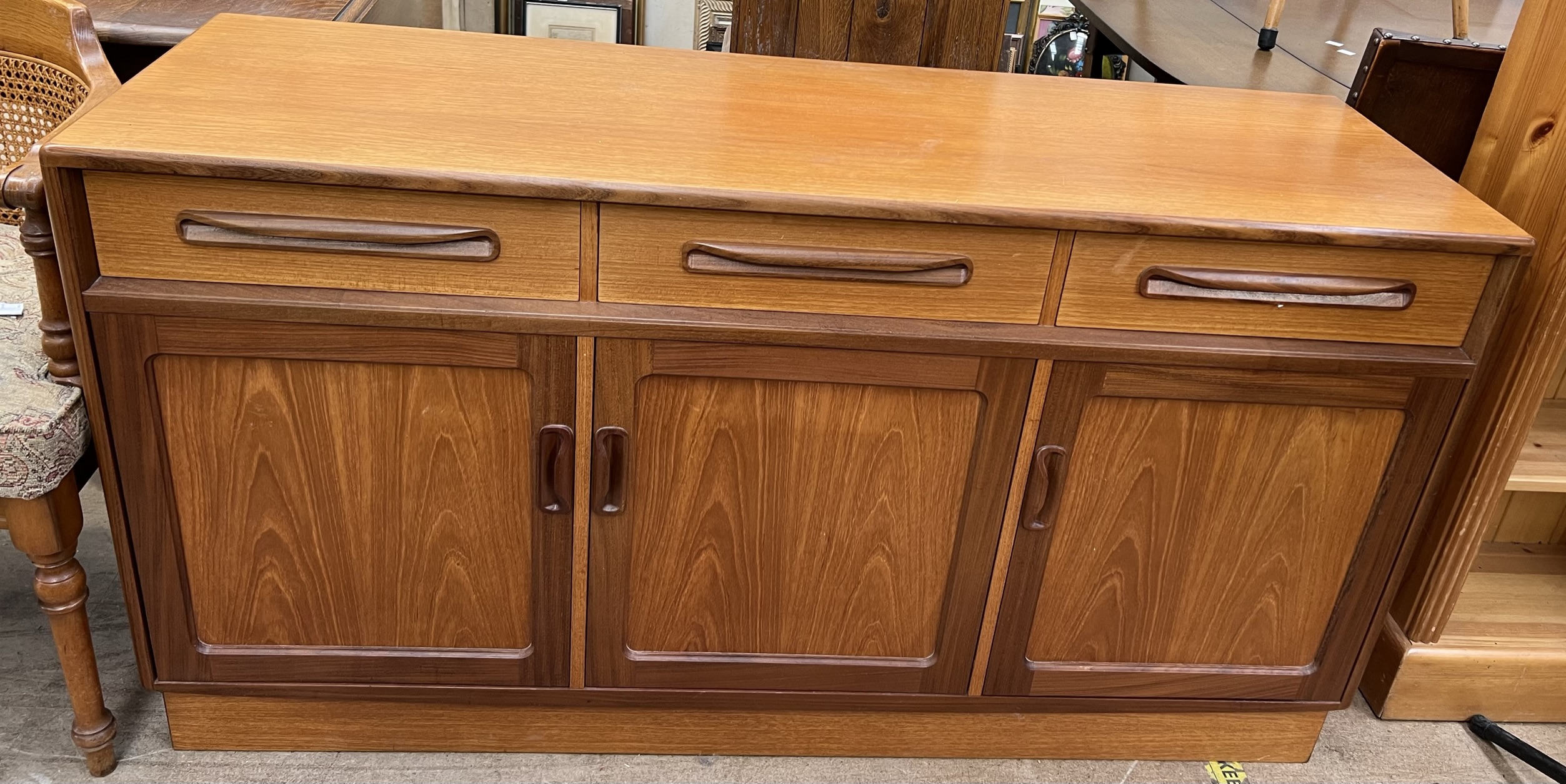 A mid 20th century G-Plan teak sideboard with three drawers above three cupboards on a plinth base,