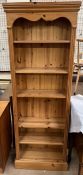 A modern pine bookcase with a moulded cornice above shelves on a plinth