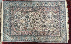 An Iranian rug with a cream ground and scrolling flowers and leaves with pink and blue guard