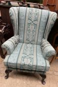 A wing back upholstered chair with cabriole legs and pad feet