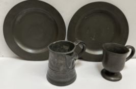 Two pewter plates together with a goblet and a spouted tankard