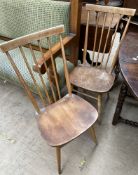 A pair of Ercol teak stick back dining chairs on tapering legs