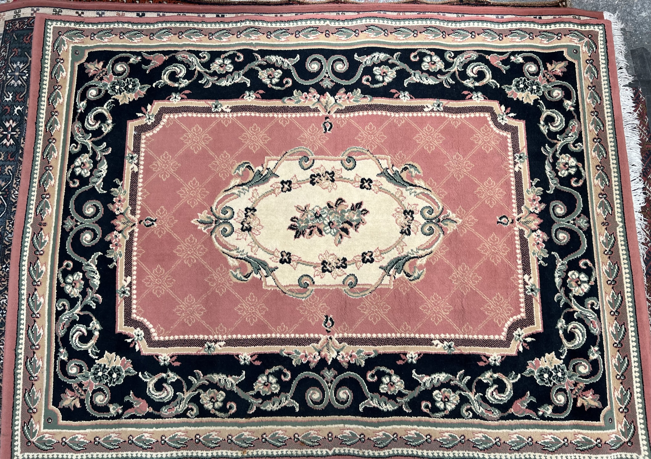 A modern rug with a central pink field with black and pink guard stripes decorated with scrolling