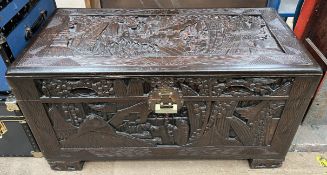 A carved Chinese camphor wood coffer decorated with trees and figures