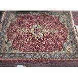 A room size Wilton rug with a red ground and central medallions,