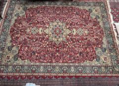 A room size Wilton rug with a red ground and central medallions,