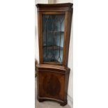 A 20th century mahogany standing corner cupboard of dished shape