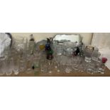 Cut glass jugs together with a collection of drinking glasses, glass bowls, mirror,