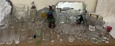 Cut glass jugs together with a collection of drinking glasses, glass bowls, mirror,