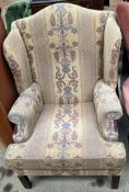 A George III style wing back chair with patterned floral upholstery on square legs