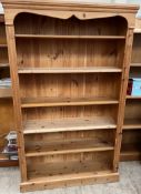 A modern pine bookcase with a moulded cornice above six shelves on a plinth base