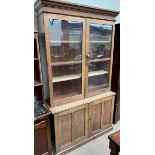 A 20th century oak bookcase with a moulded cornice above a pair of glazed doors the base with a