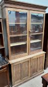 A 20th century oak bookcase with a moulded cornice above a pair of glazed doors the base with a