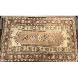 A rug with a cream ground, with central medallions and numerous guard stripes,