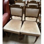 A set of four Edwardian dining chairs with a leaf carved upholstered back above pad upholstered