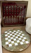 A two tone metal chess set contained within a glass display cabinet together with a circular onyx