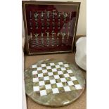 A two tone metal chess set contained within a glass display cabinet together with a circular onyx