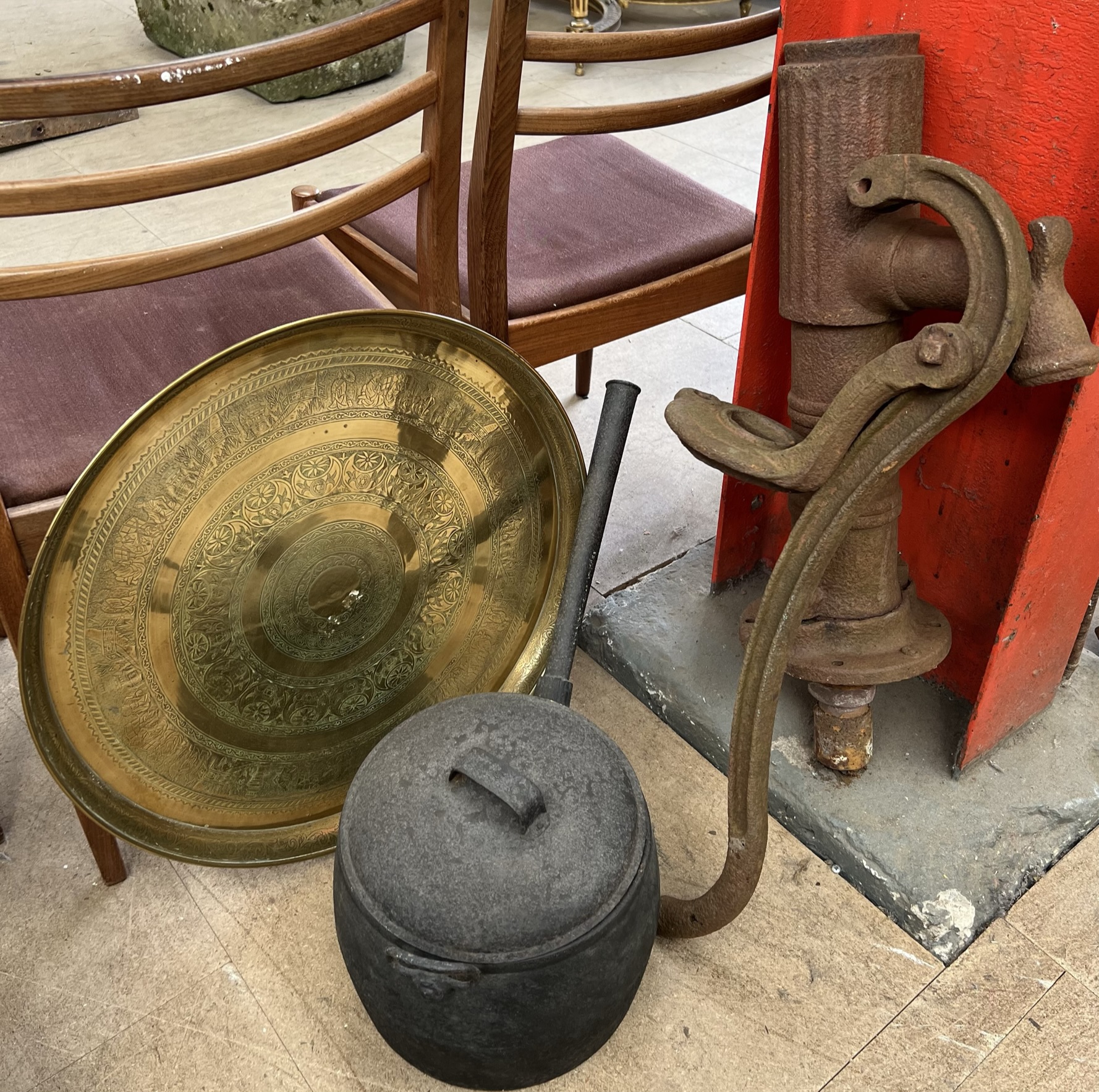 A cast iron water pump together with a cast iron sauce pan and a brass tray table top