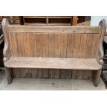 A pine pew bench with carved ends and a panelled back