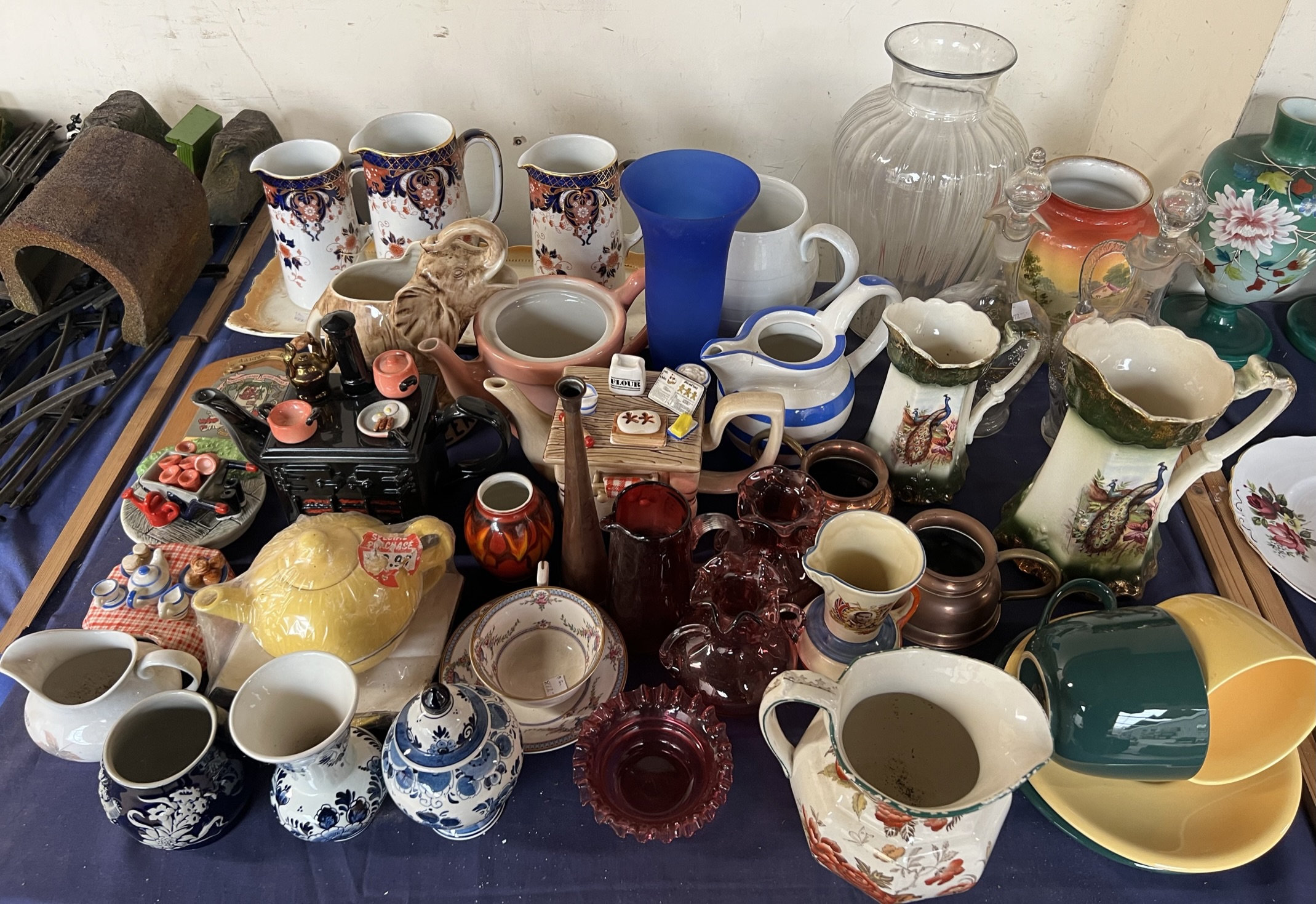 Graduated pottery jugs together with glass decanters, novelty teapots,
