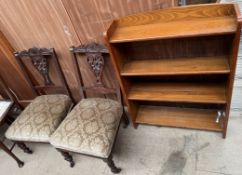 A pair of Edwardian carved salon chairs together with a bookcase