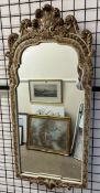 A gilt and cream wall mirror with feather carving to the top
