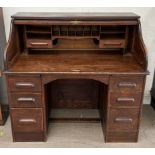 A 20th century oak roll top desk with a serpentine tambour front enclosing a fitted interior of