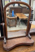 A Victorian mahogany toilet mirror with a domed plate and a shaped base