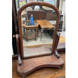 A Victorian mahogany toilet mirror with a domed plate and a shaped base